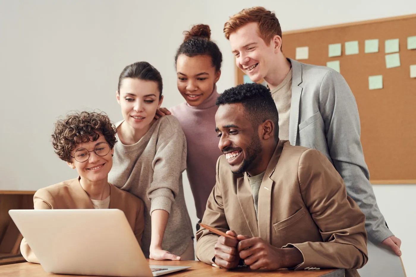 Equipo sonriendo mientras trabaja junto frente a una laptop